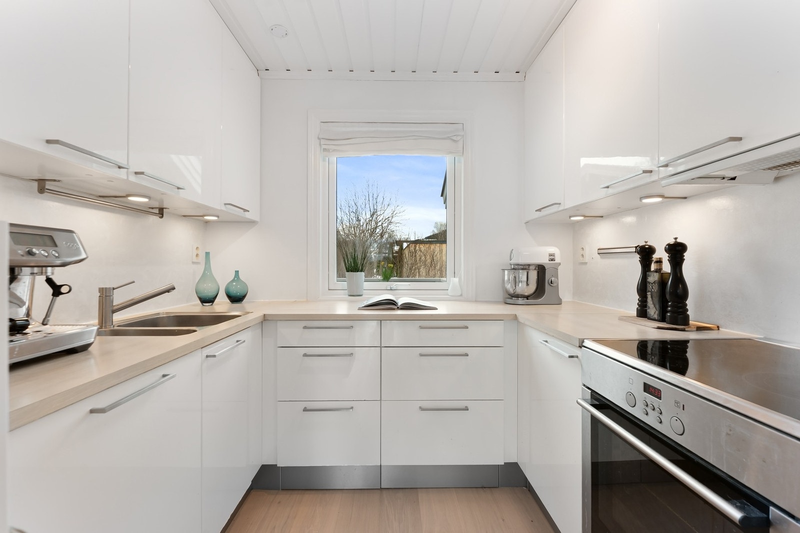 Kjøkkenet fremstår moderne med glatte fronter og benkeplate i laminat. Galleribilde