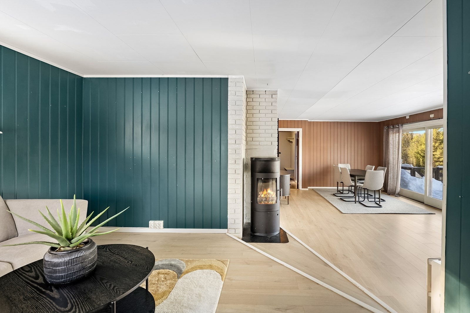 Stuen har store vindusflater og utgang til terrasse som strekker seg langs to sider av huset. Galleribilde