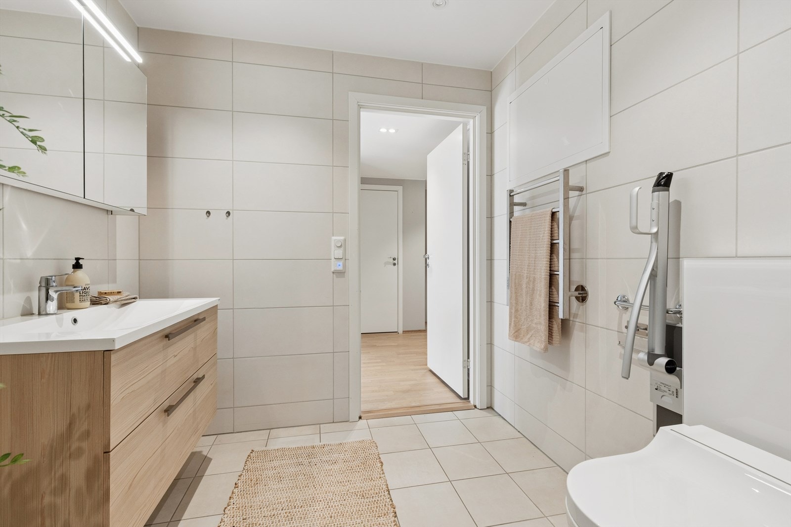 Baderomsinnredningen består av eikefargede, glatte fronter med romslige skuffer og en heldekkende servant. Over innredningen er det speilskap med integrert belysning. Galleribilde