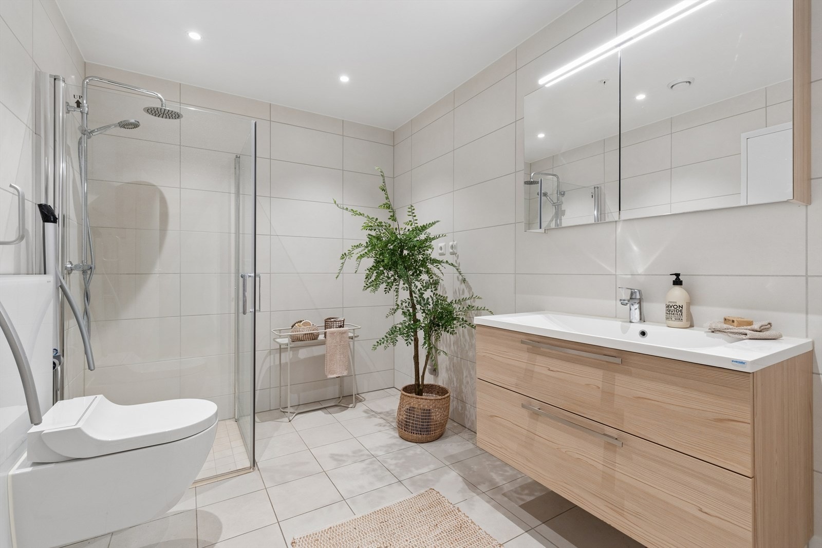 Badet fremstår moderne og stilrent, med store, lyse fliser som gir rommet et tidsriktig uttrykk. Galleribilde