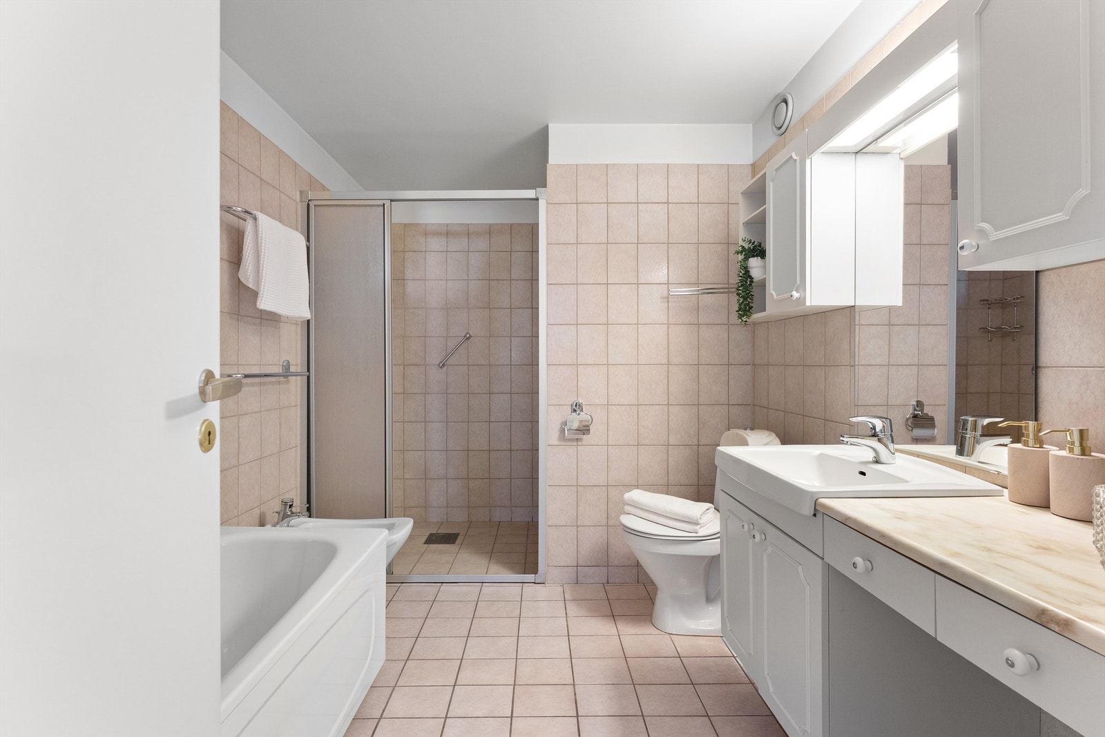 Leiligheten har to bad. Dette badet i gangen er flislagt og har både dusjhjørne og bidé. Galleribilde