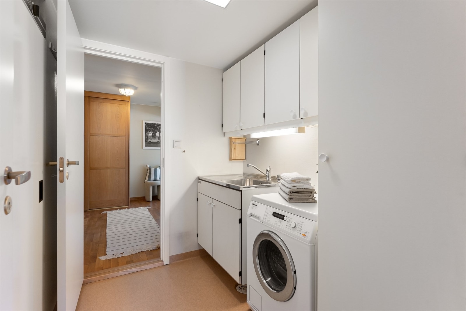 Et separat og praktisk vaskerom med nedfelt servant og opplegg for vaskemaskin. Galleribilde