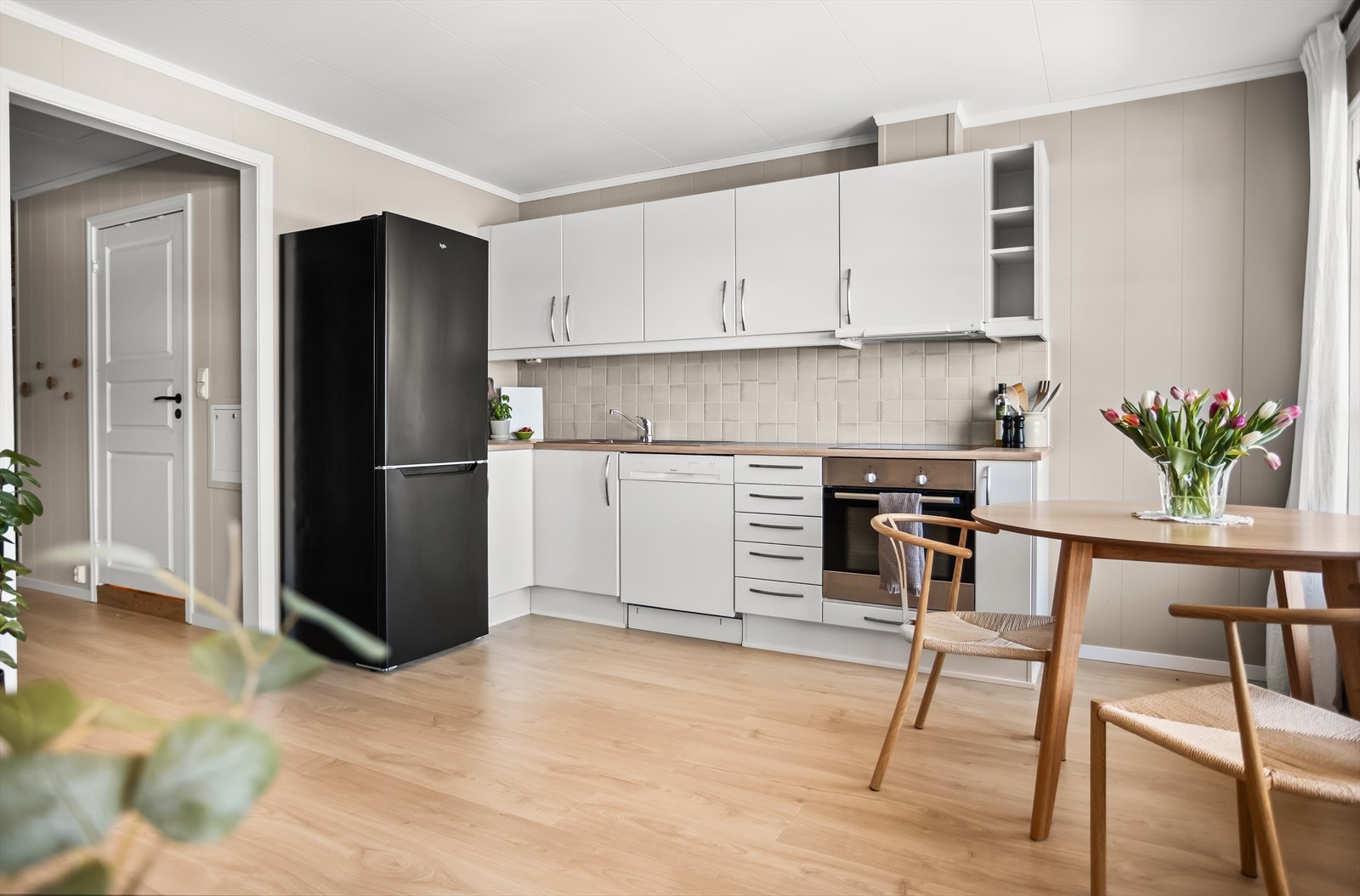 Det er fliser på veggen mellom benk og overskap, med belysning under overskapene. Galleribilde