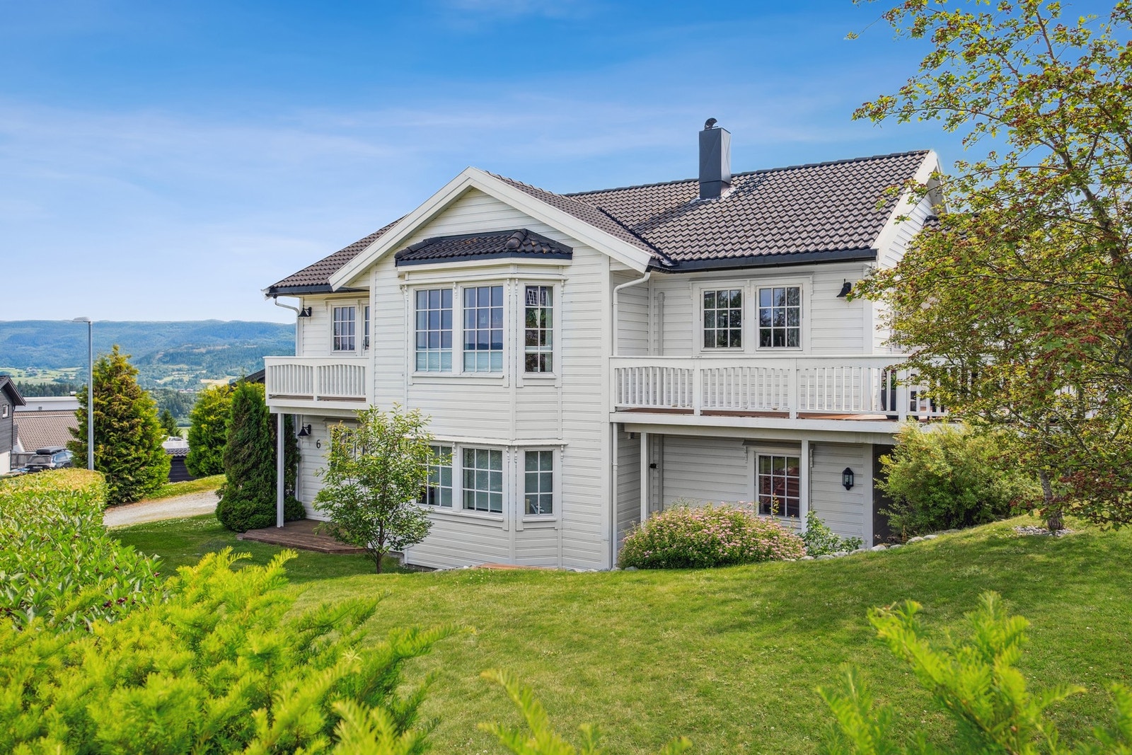 Sommerbilde av eiendommen. Store og fine plenområder med masse boltreplass Galleribilde