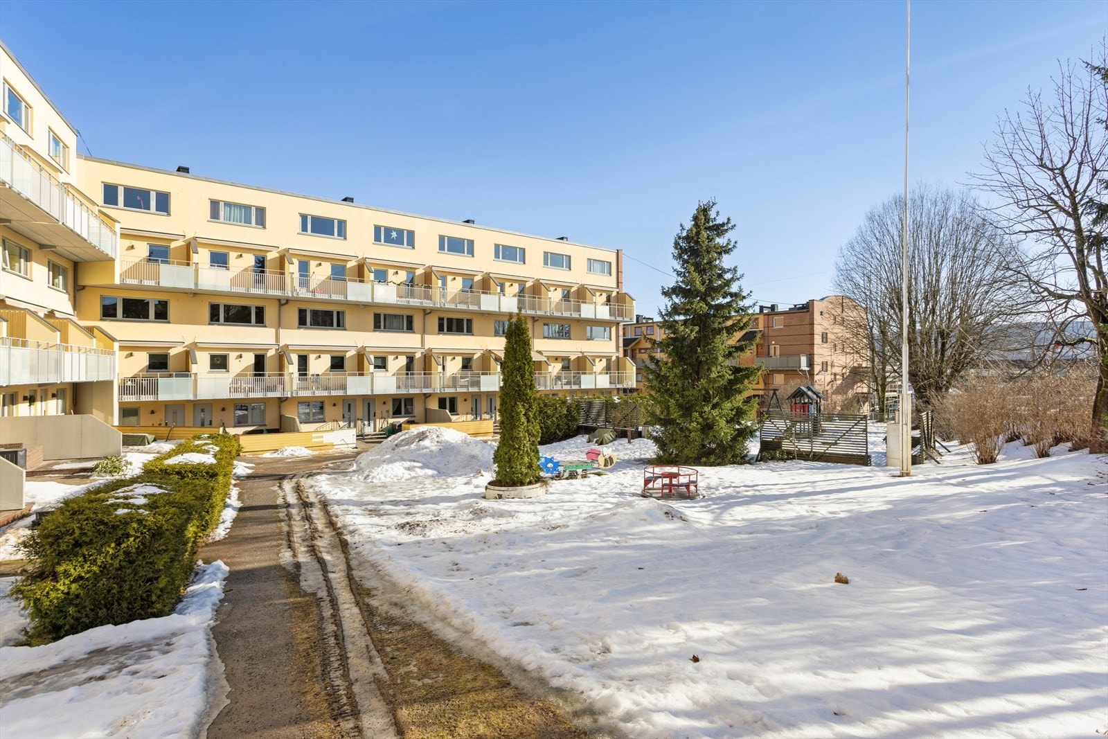 Pent opparbeidet grøntarealer med busker, trær, lekeplass m.m. Galleribilde