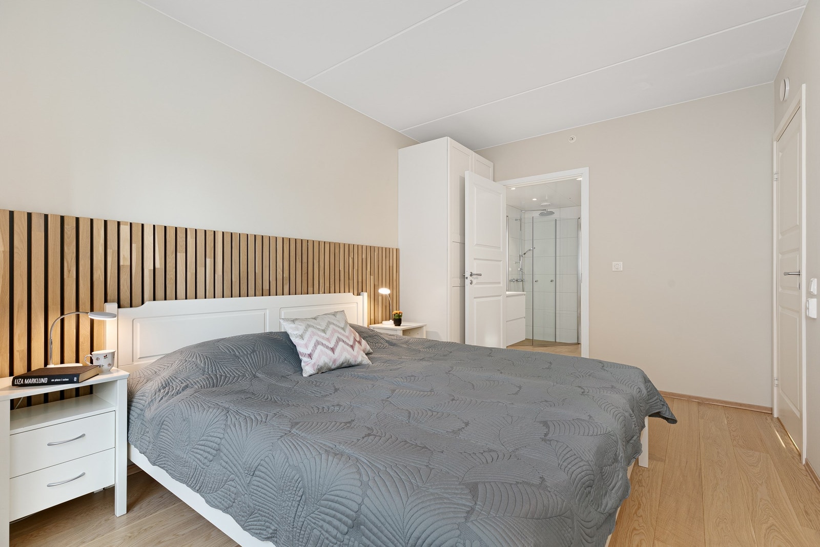 Rommet er malt i lyse farger, med akustikkpanel bak sengen som gir inntrykk av en forlenget sengegavl. Galleribilde