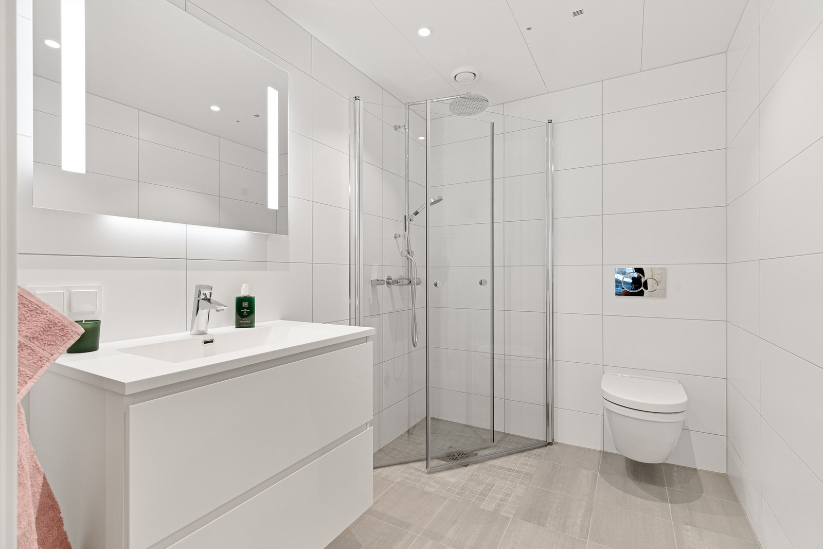 Baderom fra byggeår. Flislagt gulv med varme og flislagte vegger. Himlingsflate med hvite metallplater med downlights. Vegghengt servantskap
med glatte fronter. Heldekkende servant og vegghengt speil med integrert lys. Dusjhjørne med svingbare glassdører. Galleribilde