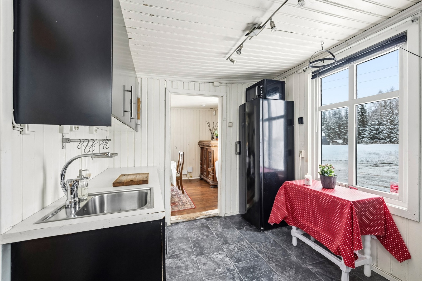 Kjøkkenet sett fra motsatt side viser en praktisk arbeidssone med oppvaskkum, skapplass og benkeplate. Planløsningen er kompakt, men funksjonell - og gir et godt utgangspunkt for videre oppgraderinger. Galleribilde