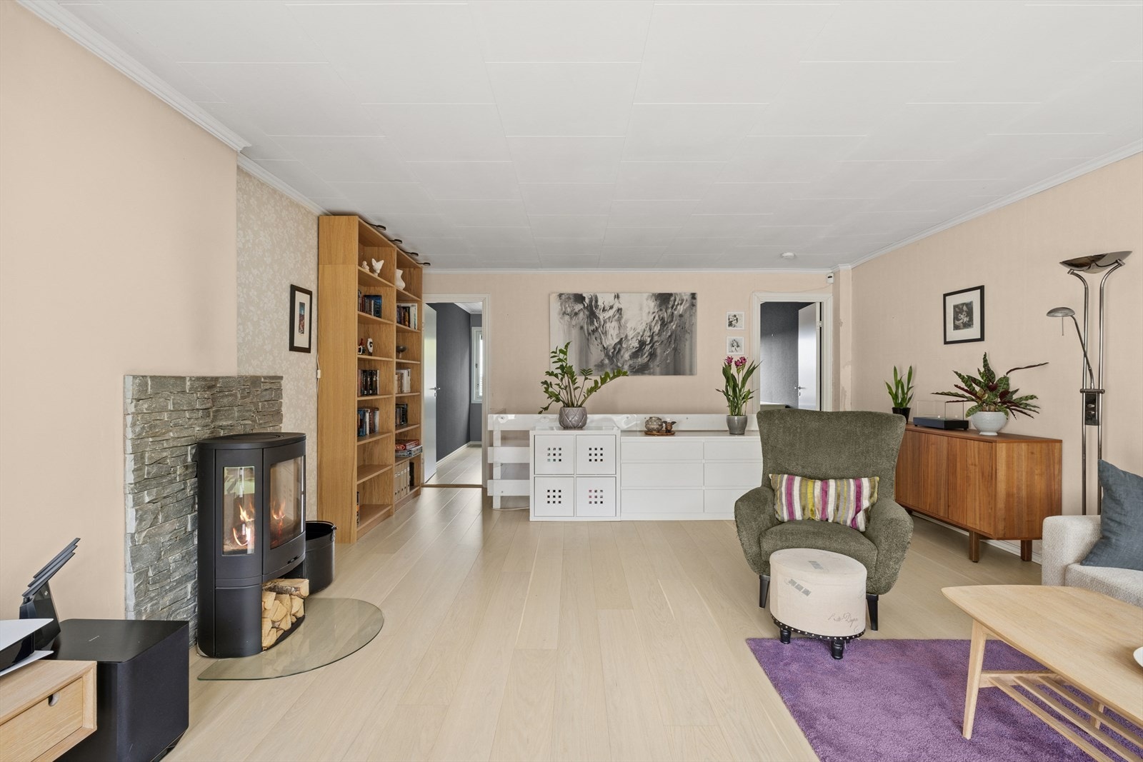 Tiltalende og lekker stue med peisovn i senter av rommet. Den gjennomgående enstavsparketten tilfører rommet et eksklusivt og helhetlig uttrykk. Galleribilde