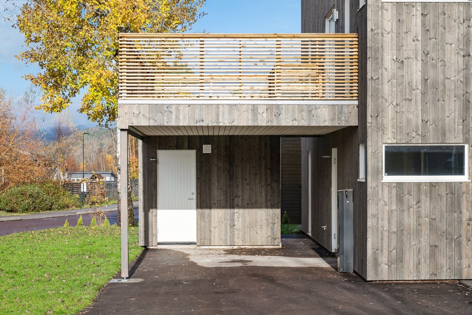 Innenfor boligens carport er det en sportsbod og over er verandaen. Galleribilde
