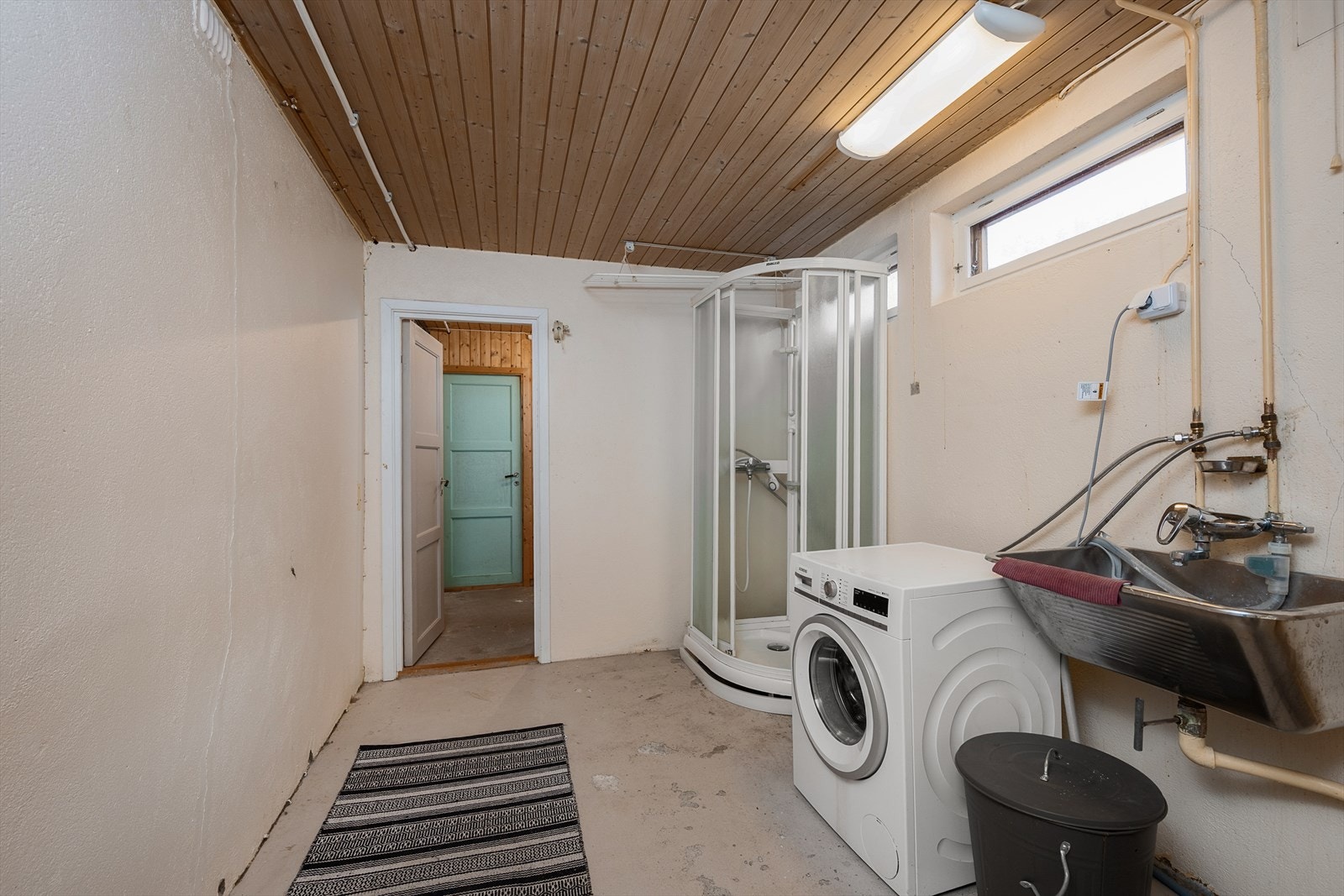 Stort og praktisk vaskerom med dusjkabinett, utslagsvask og opplegg for vaskemaskin. Galleribilde