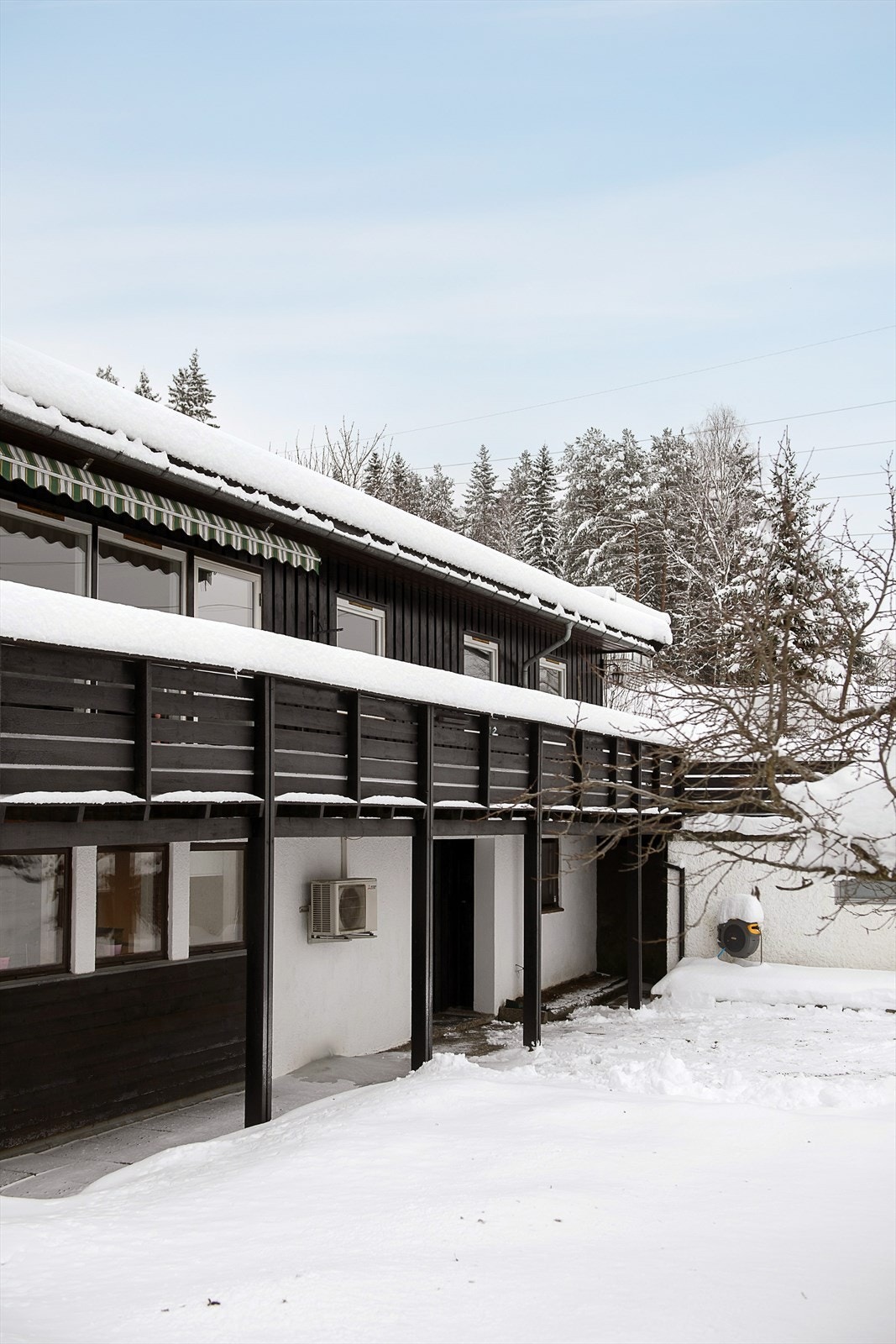 Boligen har en overbygget veranda og uteplass som strekker seg langs store deler av fasaden. Galleribilde