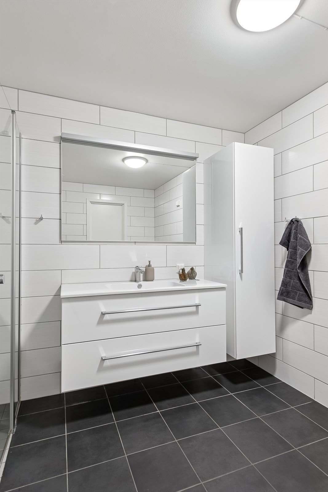 Tidsriktig baderomsinnredning med skuffeseksjon, heldekkende servant og høyskap. Galleribilde