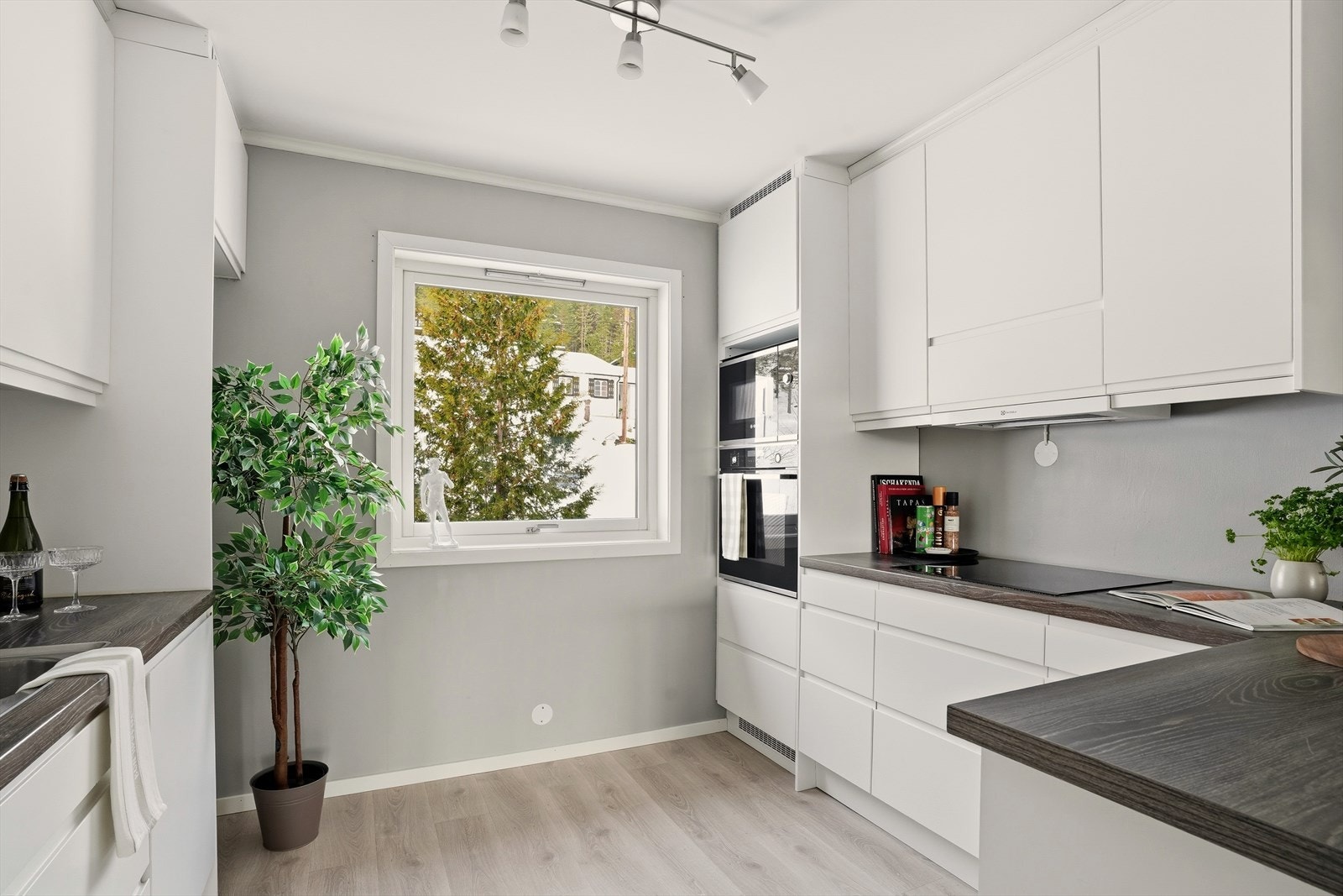 Kjøkkeninnredningen har lyse, slette fronter og en mørkere laminat benkeplate Galleribilde