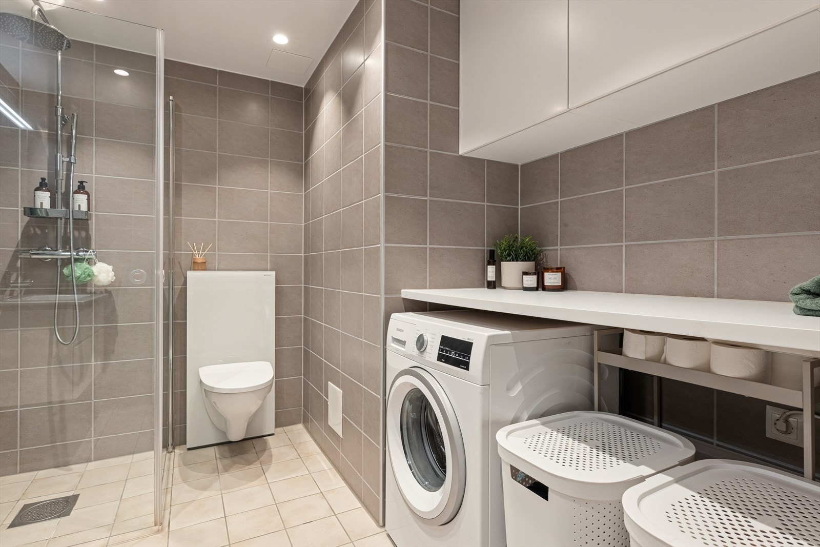 Badet har en praktisk vaskeromsdel med plass til vaskemaskin og tørketrommel, praktisk benkeplass og ekstra skapplass. Galleribilde