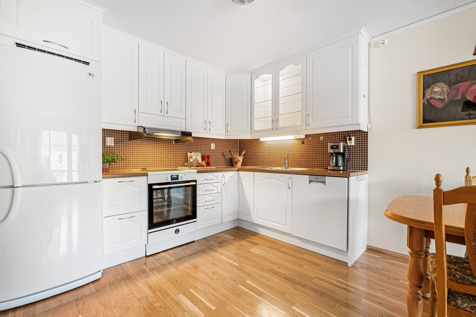 Tidløst kjøkken med hvite profilerte fronter og benkeplate av typen laminat. Galleribilde