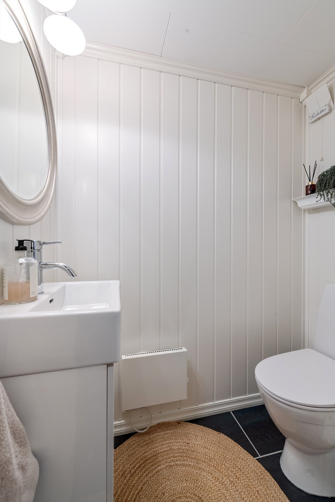 Praktisk toalettrom i underetasjen med flislagt gulv og servantinnredning Galleribilde