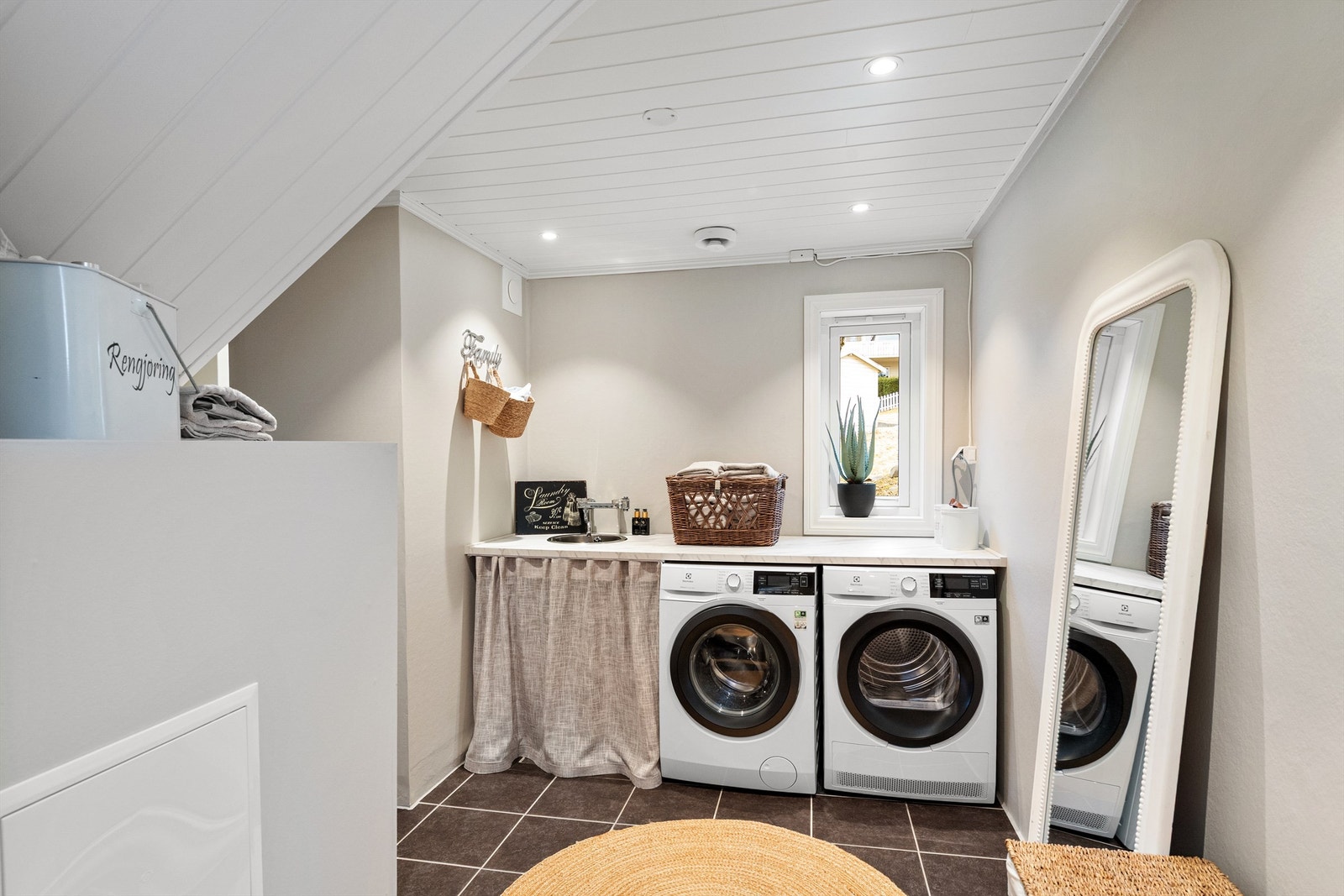Separat vaskerom med opplegg for vaskemaskin og tørketrommel under en praktisk benkeplate Galleribilde