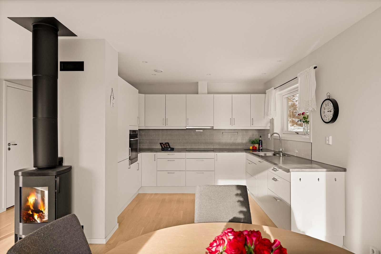 Romslig kjøkkeninnredning med integrerte hvitevarer som kjøl- og fryseskap, oppvaskmaskin, induksjonstopp og stekeovn Galleribilde