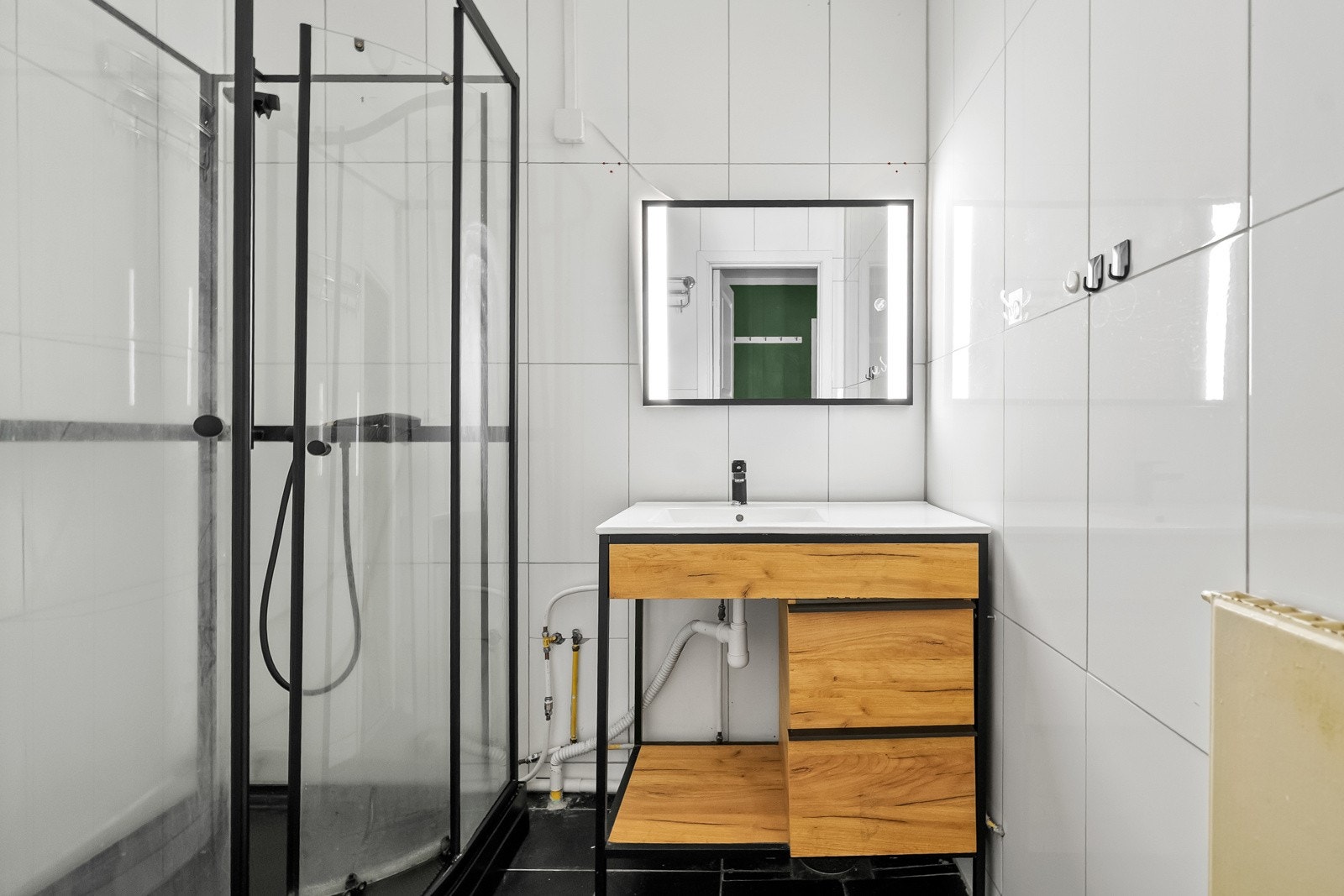 Badet er flislagt og av eldre dato, fremstår å være overflateoppusset med flis over gamle overflater. Innredningen består av servantmøblement, speil og frittstående dusjkabinett. Galleribilde