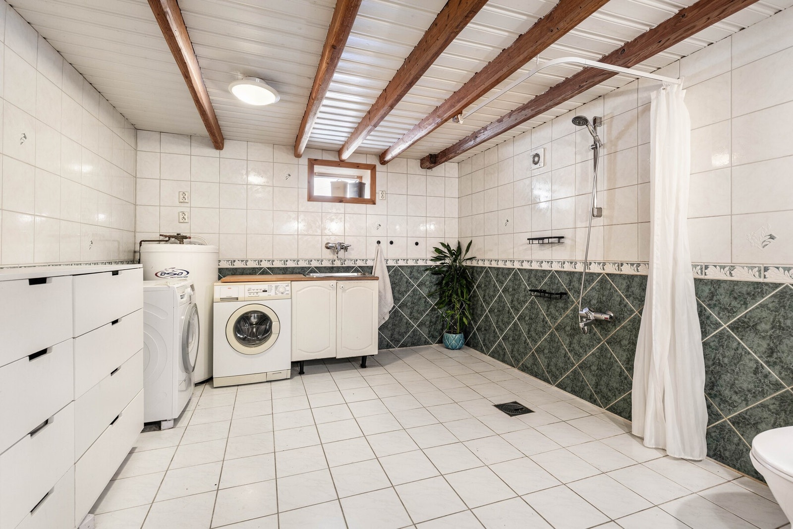 Badet er plassert i kjeller og er flislagt på gulv og vegger. Galleribilde