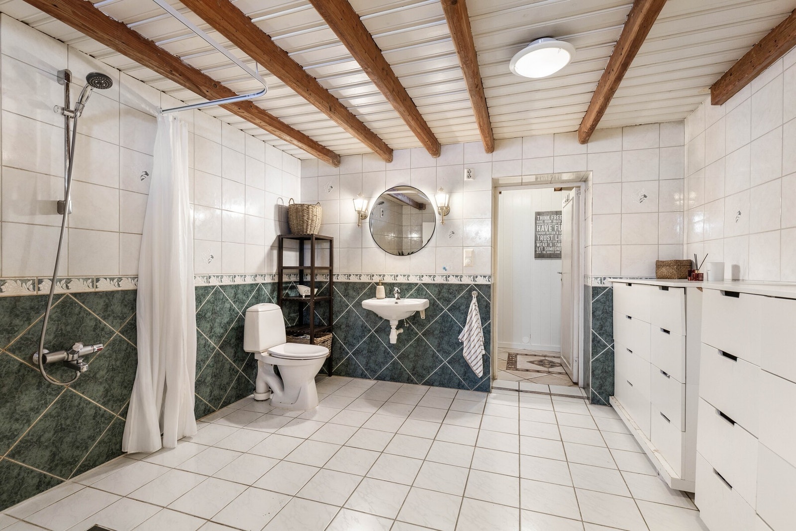 Badet har god gulvplass og fremstår funksjonelt innredet med rom for både personlig hygiene og klesvask. Galleribilde