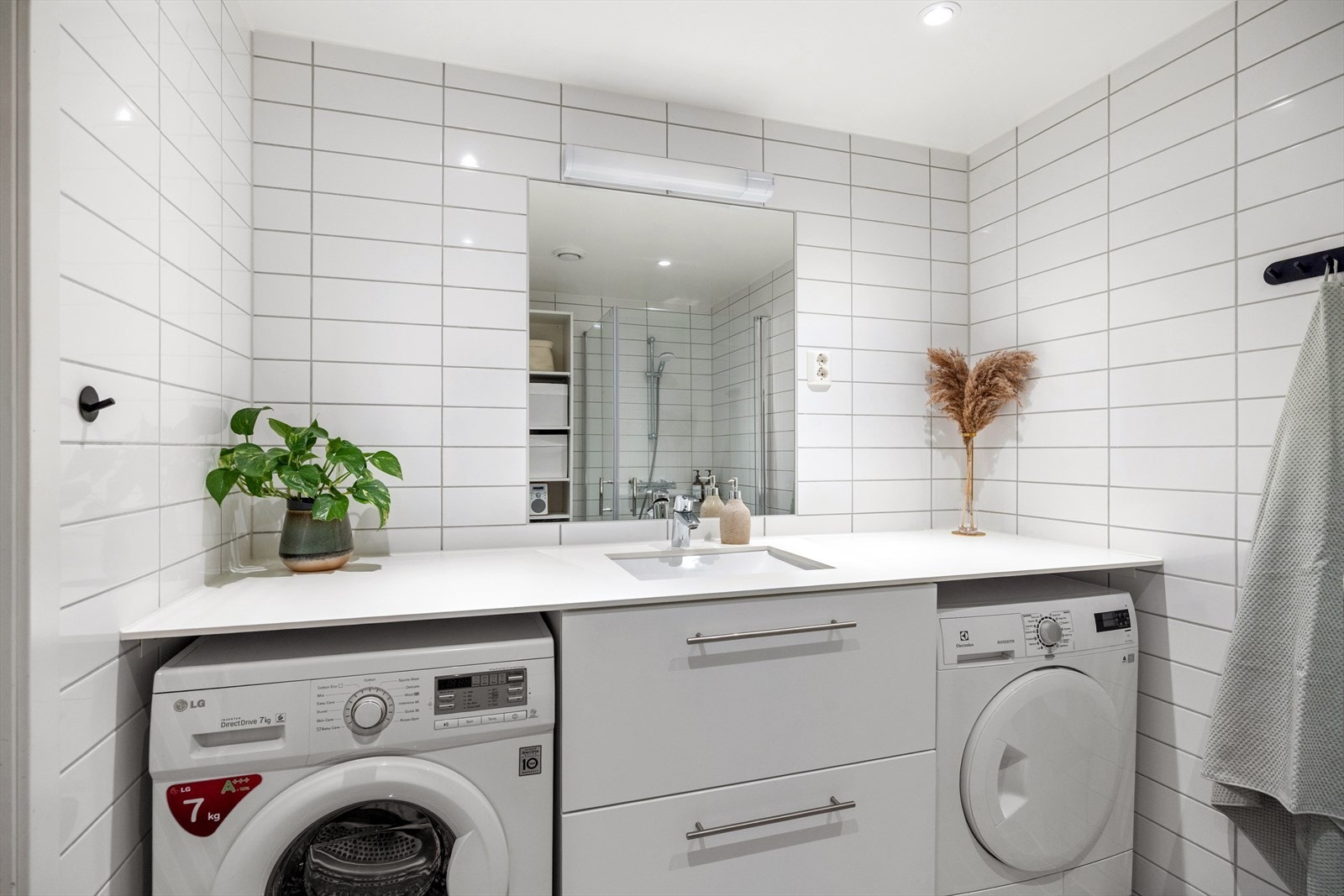 Badet er stilrent innredet med vegghengt toalett, dusjhjørne med herdet glassvegg/-dør, servant med underskap, speil og belysning. Det er også opplegg for vaskemaskin. Galleribilde