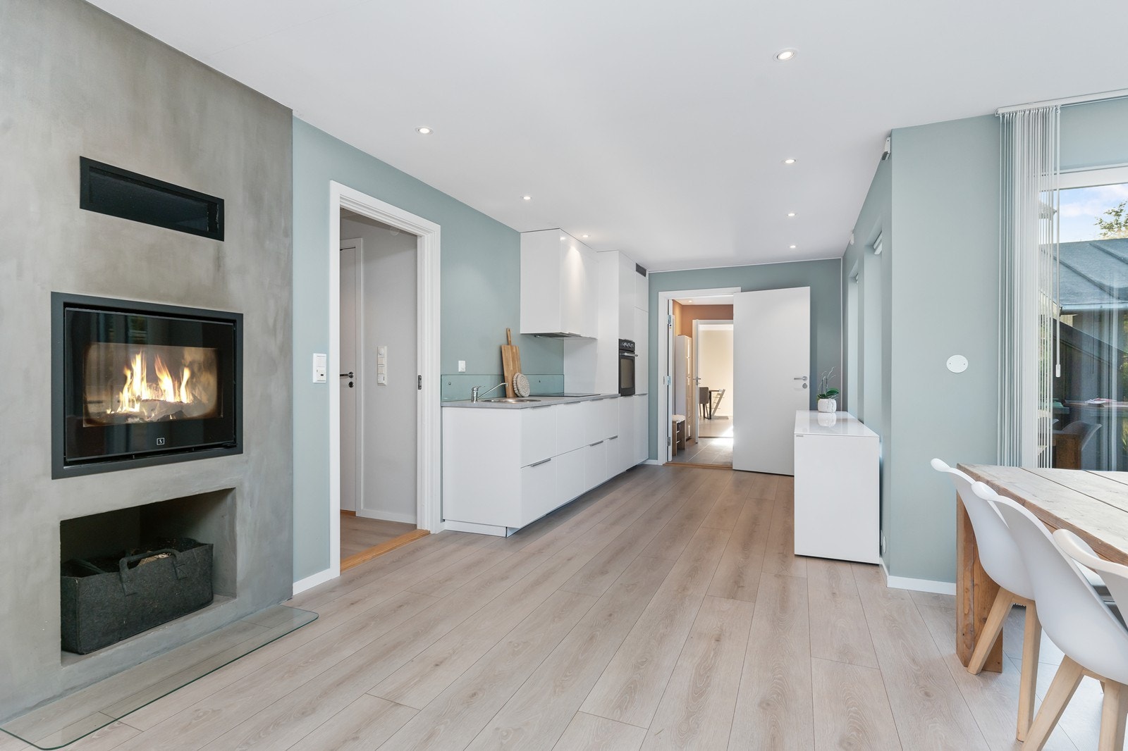 Lyst og innbydende oppholdsrom med moderne kjøkken og stilren peis. Galleribilde