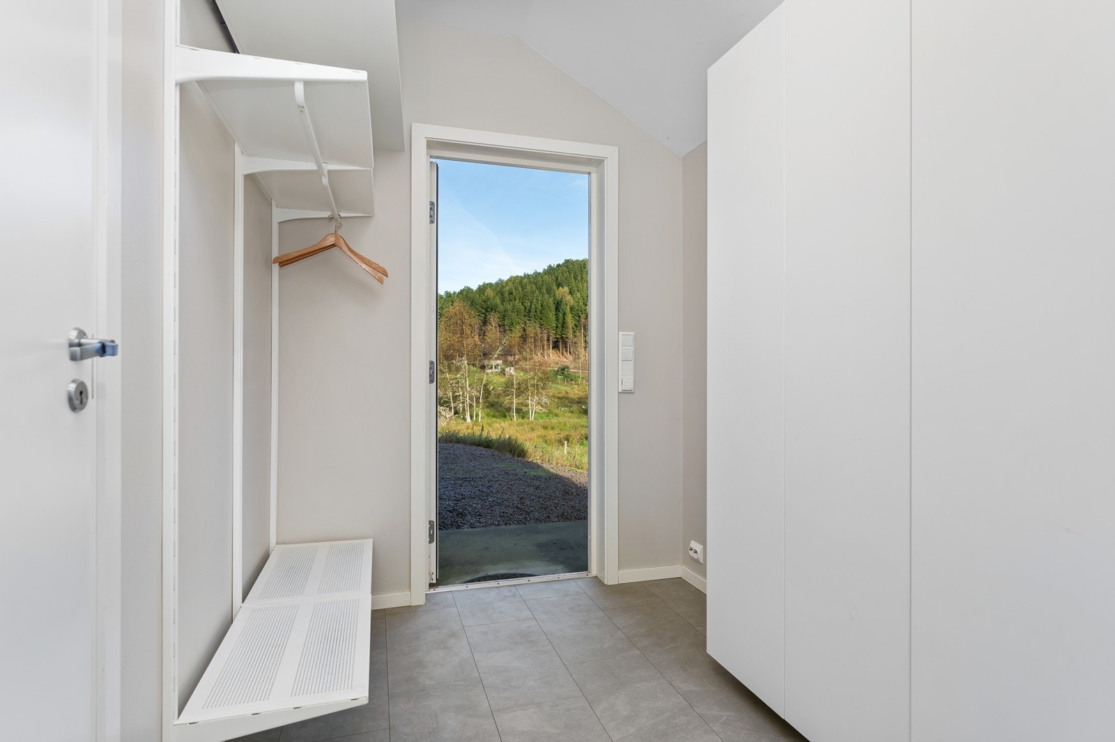 Inngangsparti til hoveddel er på baksiden og kan være en praktisk grovinngang dersom man skal benytte hele boligen selv. Her er flislagt gulv med elektriske varmekabler og god plass til garderobeløsning. Galleribilde
