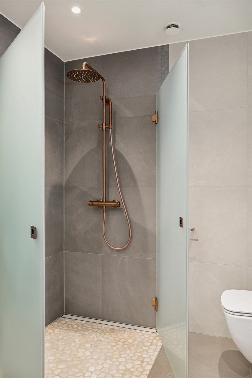 Gulvet er flislagt, med rullestein i dusjsonen. Galleribilde