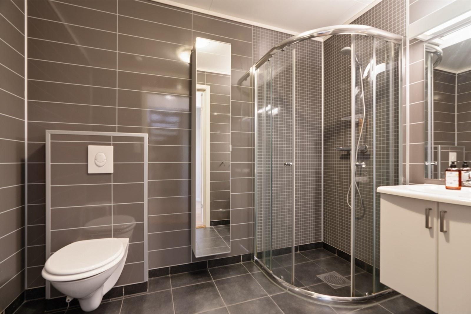 Badet har våtromsplater på veggene og fliser på gulvet. Galleribilde