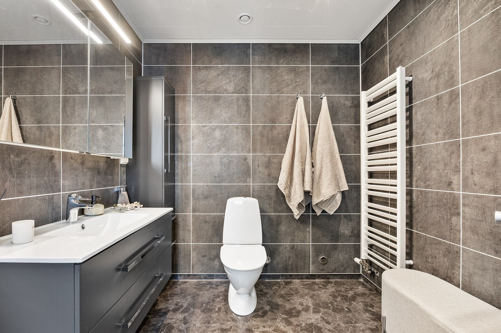 Badet har varmekabler i gulvet, spotter i taket og en praktisk håndkletørker. Galleribilde