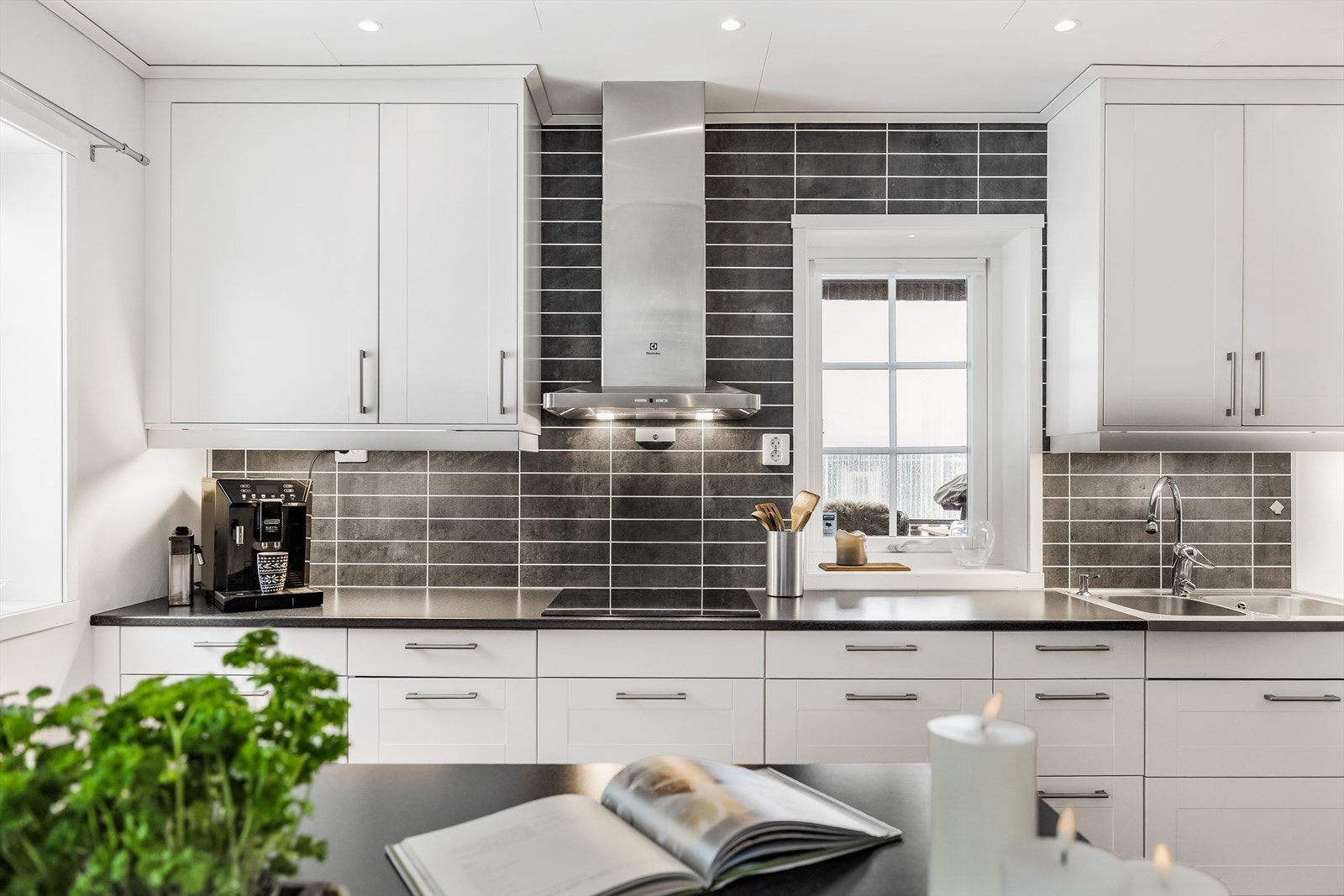 Sorte kitchenboard mellom benk og overskap gir en fin kontrast til den hvite innredningen. Galleribilde