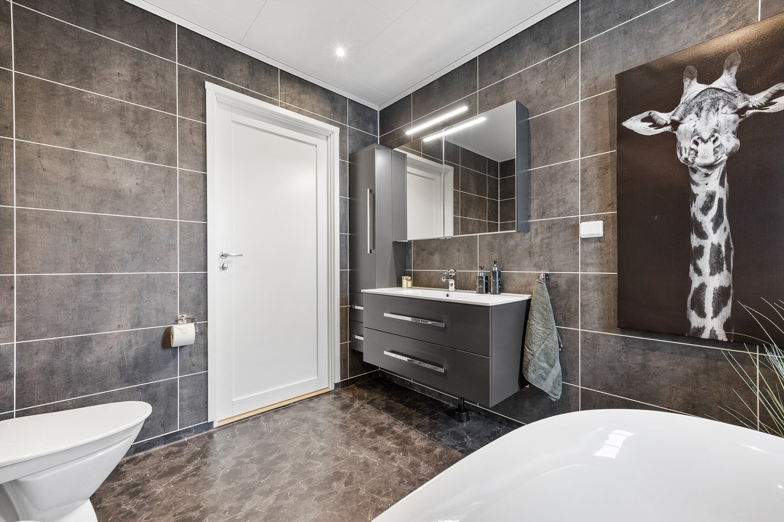 Innredningen består av servantskap, gulvstående toalett, speil på vegg og belysning. Galleribilde