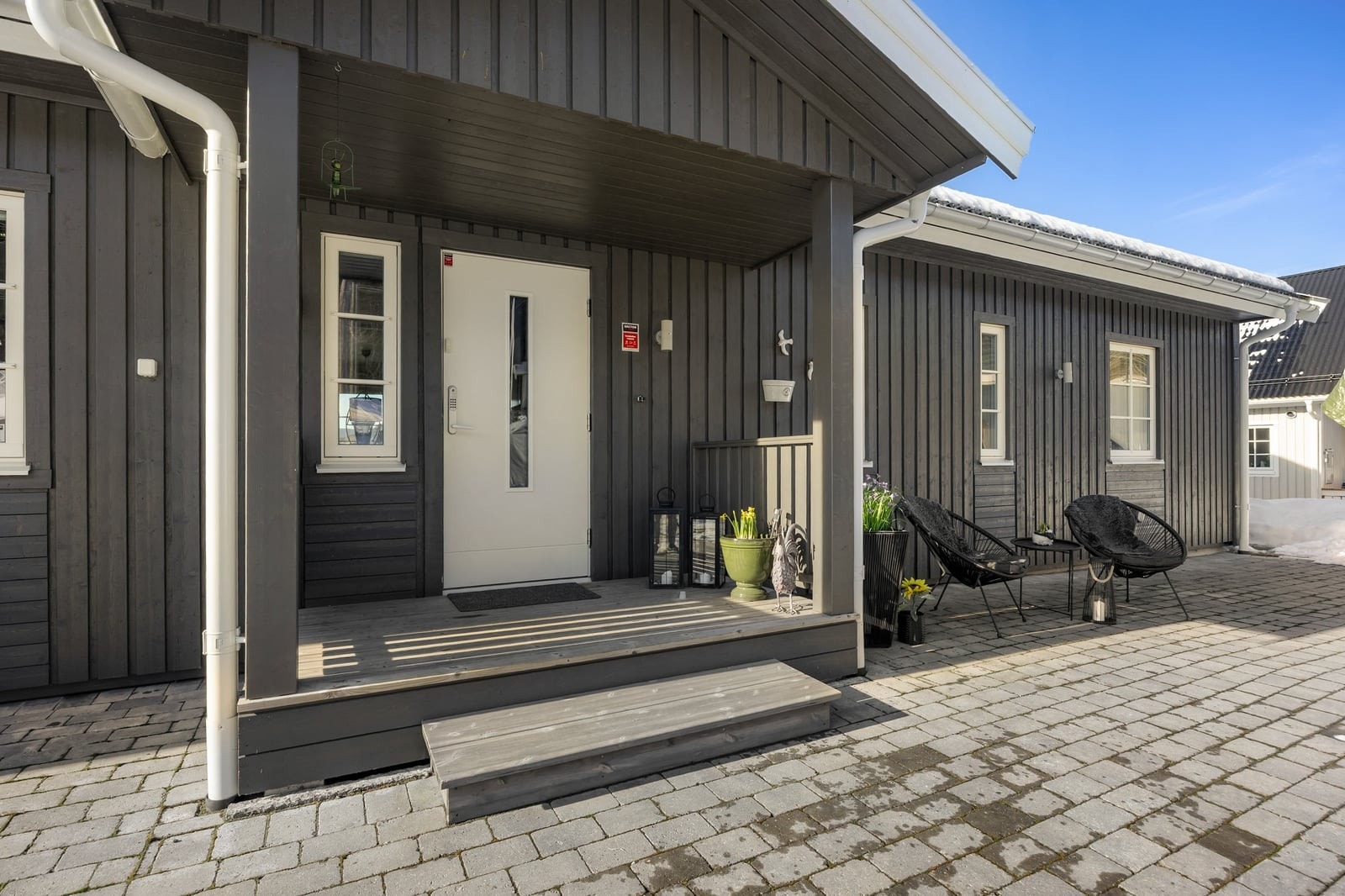 Overbygget inngangsparti og en gårdsplass delvis lagt med belegningsstein. Galleribilde