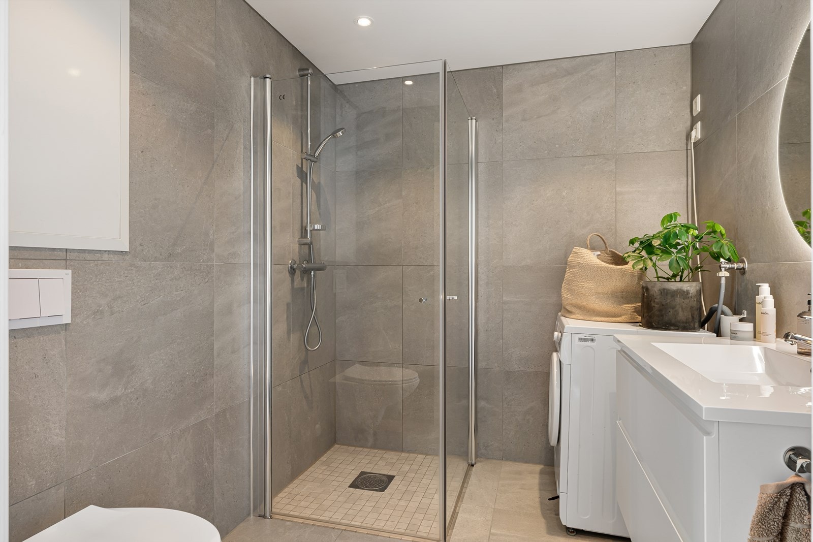 Badet fremstår som arealeffektivt med pen baderomsinnredning i hvit utførelse. Opplegg for vaskemaskin og tørketrommel kan også nevnes. Galleribilde