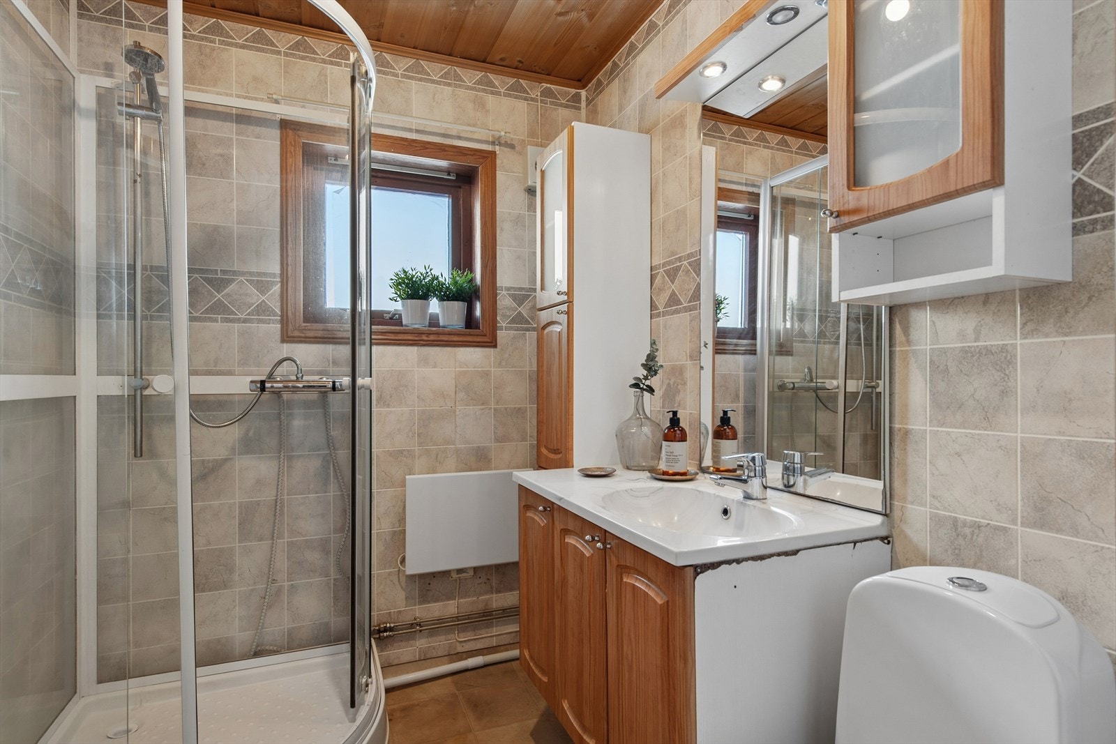 Badet i 1. etasje er utstyrt med baderomsinnredning med servant og ett-greps blandebatteri, WC og dusjkabinett. Galleribilde