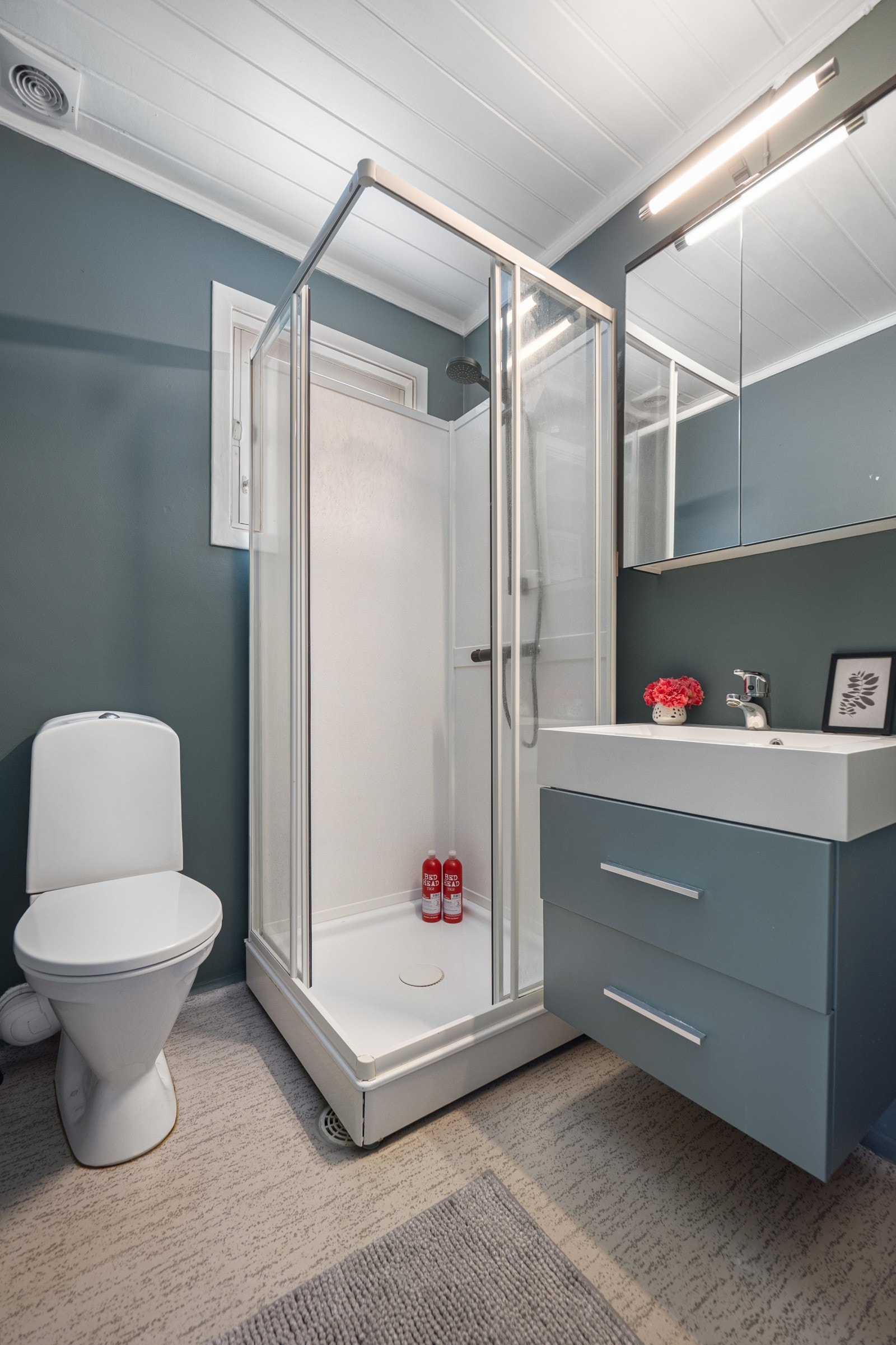 Badet er innredet med servantinnredning, servant, dusjkabinett og toalett. Galleribilde