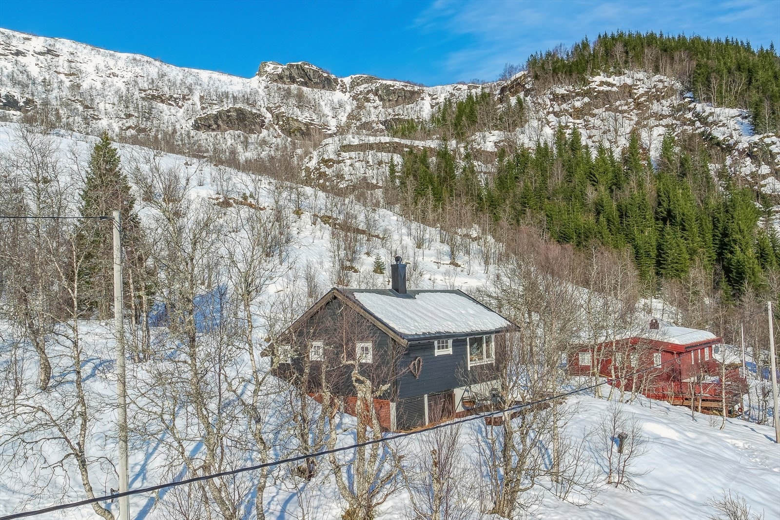 Hytten ligger mot toppen i et lite hyttefelt med spredt bebyggelse Galleribilde
