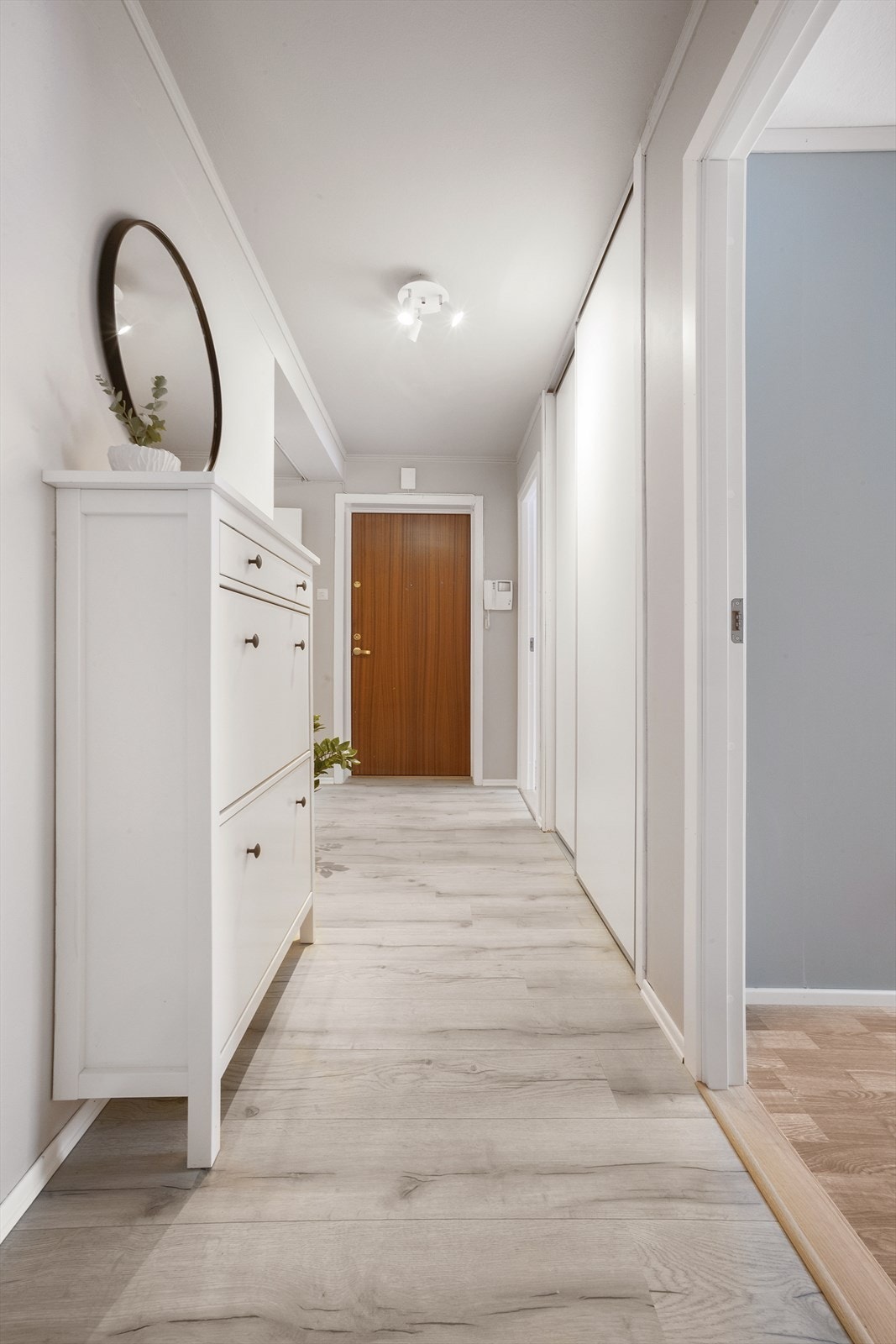 Man kommer inn i en innbydende entré med laminat på gulv og lysmalte vegger Galleribilde