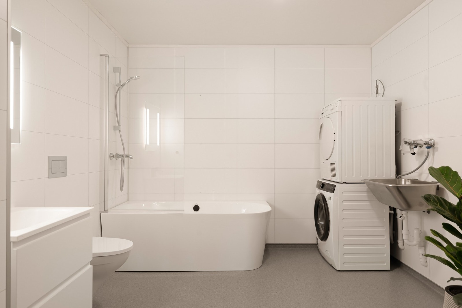 Delikat baderom/vaskerom med badekar, opplegg for vaskemaskin/plass til tørketrommel, toalett og servantinnredning. Galleribilde