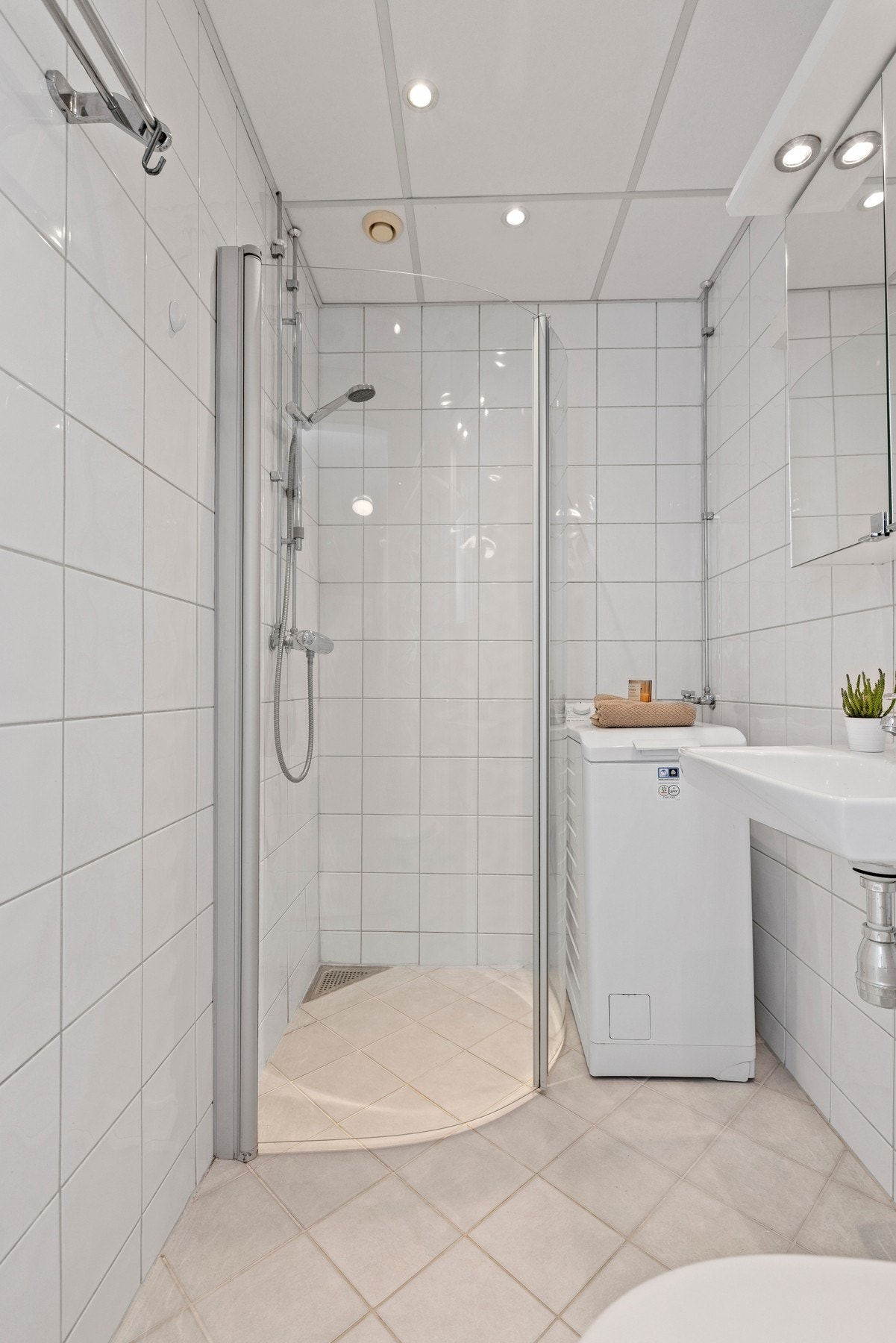 Badet har vegghengt toalett med innebygd sisterne kasse, vegghengt servant og vegghengte dusjdører i glass. Galleribilde