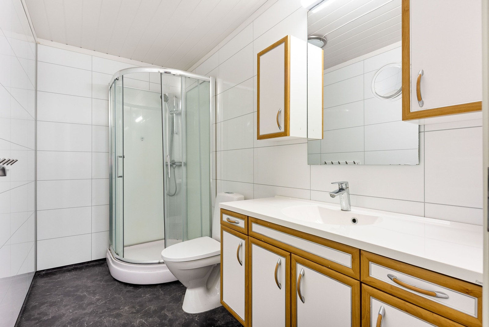 Bad med dusjkabinett, innredning med vask og toalett. Galleribilde