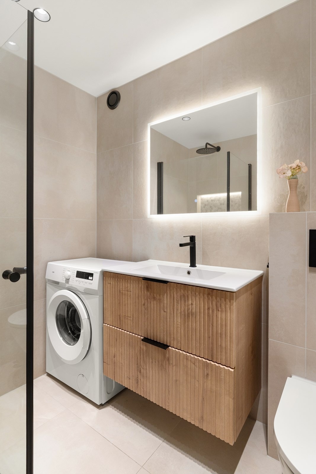 Baderommet er velutstyrt med blant annet baderomsinnredning med to skuffer, speil med lys og sort blandebatteri Galleribilde