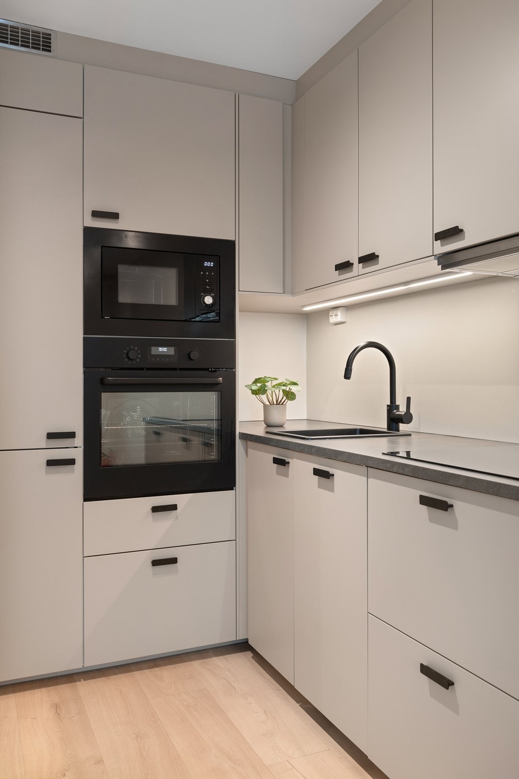 Kjøkkenet er utstyrt med intergrerte hvitvarer som oppvaskmaskin, stekeovn, mikrobølgovn, koketopp med ventilator over og kombiskap Galleribilde