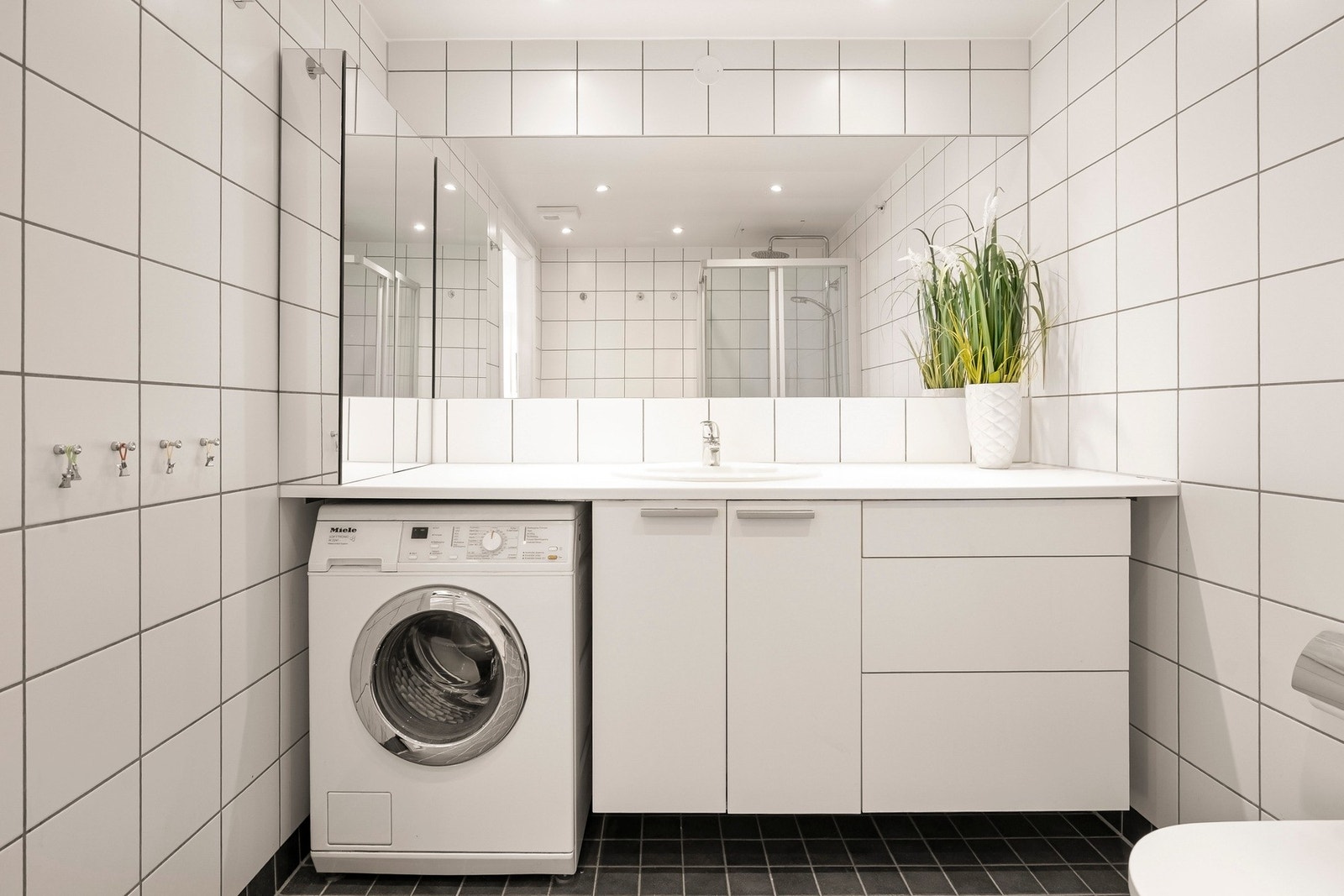 Badet er innredet med praktisk servantseksjon med skap og skuffer, samt opplegg til vaskemaskin. Galleribilde