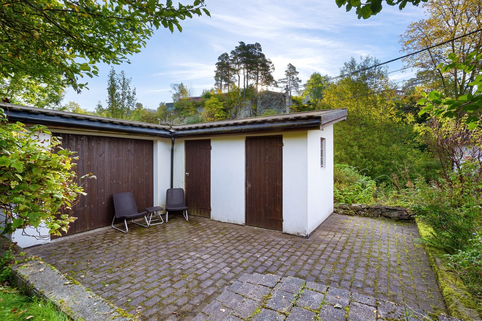 På tomten følger et frittstående tilbygg/bod med stenlagt gårdsplass i belegningsstein. Galleribilde