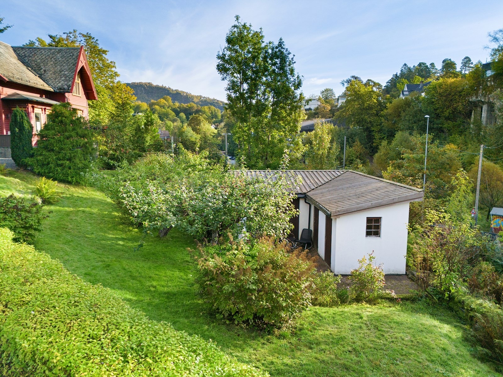 Tomten er pent opparbeidet i lett skrånende terreng, med plenarealer og variert beplantning som gir et grønt og trivelig uteområde. Galleribilde