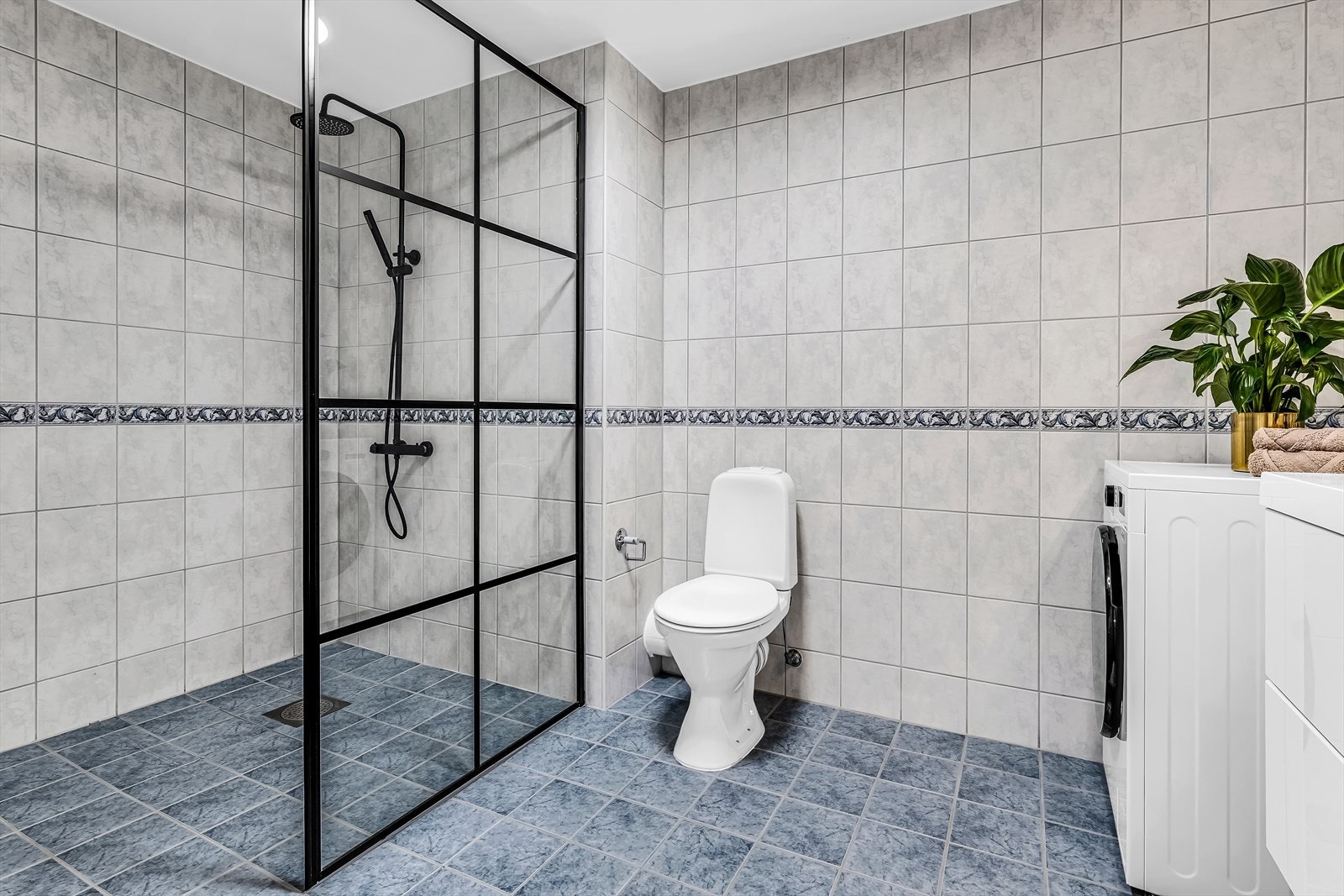 Baderommet er fra byggeår og har dusjvegg i glass, gulvmontert toalett og skuffeinnredning med heldekkende servant og ettgreps blandebatteri. Galleribilde