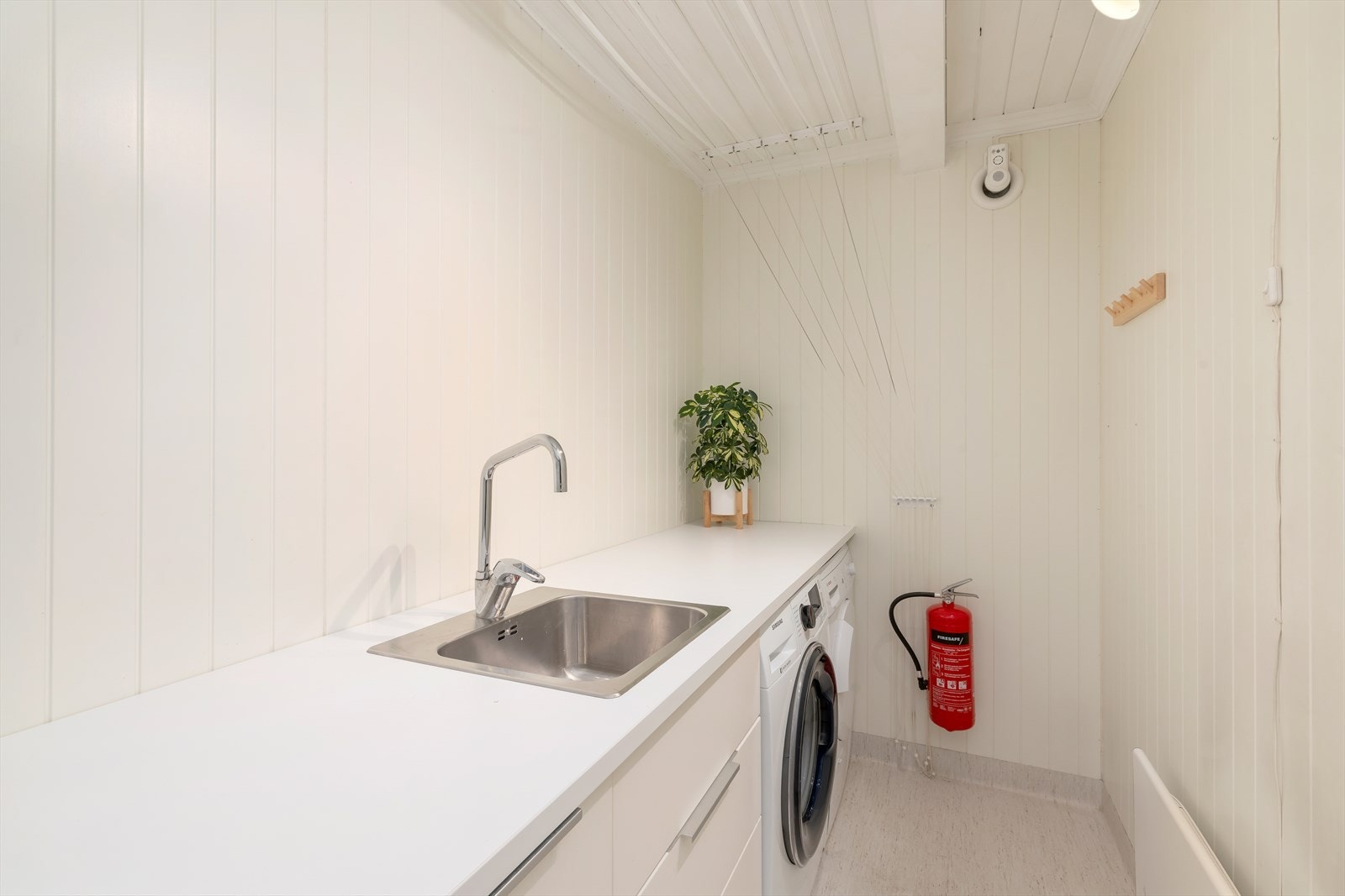 Pent og funksjonelt vaskerom i tidløs utførelse. Legg merke til smart klesoppheng. Galleribilde